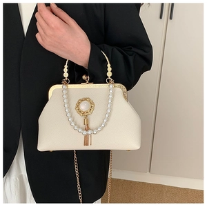 Close-up of baroque clutch bag with pearl handle, gemstone brooch and metal tassel