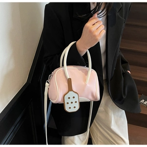 Pink macaron bowling bag with white trim and blue racket charm shown with shoulder strap