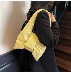 Close-up of stylish bright yellow puffy bow shoulder bag worn with a black blazer