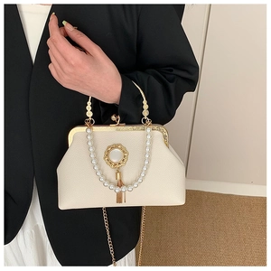 Detail of baroque style pearled handle and gold tassel clasp on cream leather handbag