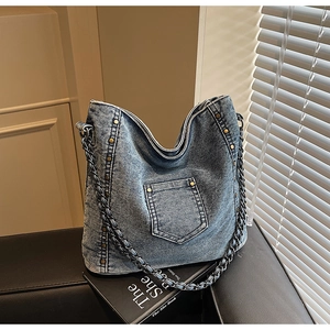 Detail of vintage blue denim bag with metallic rivets and chain shoulder strap