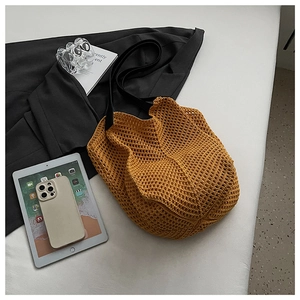 Close-up of ginger yellow hollow knit tote bag with black leather shoulder straps