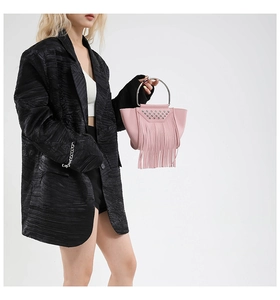 Dettaglio borsa rosa in pelle litchi con borchie argentate e lunghe frange alla moda