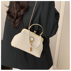 Baroque cream leather handbag with gold clasp, pearl charms, and chain strap on black blazer