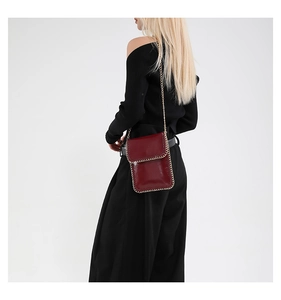 Deep red patent leather mini vertical phone bag with gold chain woven edges on model