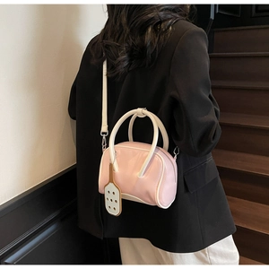 Detalle de mini bolso bowling rosa con colgante de raqueta y correa blanca ajustable