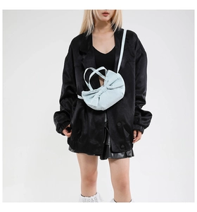 Gros plan d'un sac cabas bleu clair en forme de nœud avec texture rembourrée et bandoulière
