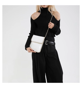 Close-up of white crossbody phone bag with metal chain woven edge and golden strap