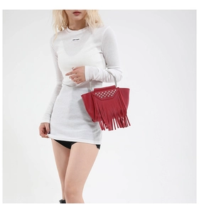 Detail of dark red rivet handbag with tassel decoration and silver metal ring handle