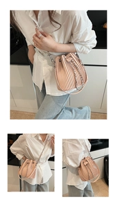 Detail view of pink pleated bucket bag with drawstring closure and silver chain strap