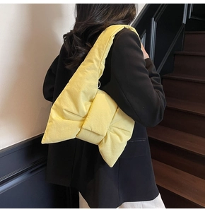 Macro shot of a light yellow quilted bow bag featuring a soft padded fabric texture