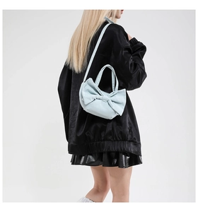 Gros plan d'un sac cabas en toile bleu clair avec un grand nœud porté par un mannequin
