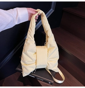 Detail of light yellow padded nylon tote bag featuring a large bow and shoulder strap