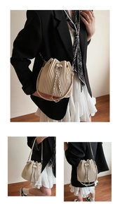 Macro view of cream pleated bucket bag showing vertical folds and drawstring closure