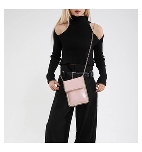 On-body view of a pink crossbody phone bag with gold chain trim and a metal strap