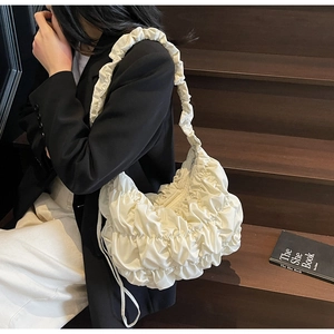 Detail of off-white pleated tote bag showing scrunched texture and ruffle strap design