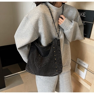 Detail of black washed denim tote bag with metal rivets and a stylish chain strap