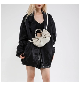 Détail d'un sac à bandoulière beige en forme de nœud sur un mannequin pour l'été