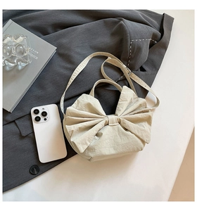 Détail d'un sac cabas crème en forme de nœud montrant la texture et la bandoulière