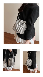Detail of grey pleated bucket bag with silver chain strap and drawstring closure