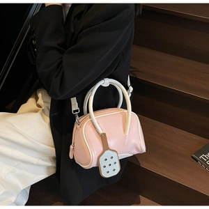 Detail of pink and white macaron bowling bag with racquet pendant on model shoulder