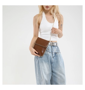 Vertical dark brown chain crossbody bag styled on a model wearing white and denim