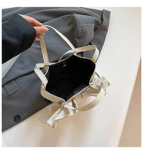 Vue de dessus du sac crème avec nœud décoratif, fermoir aimanté et tissu texturé