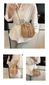 Detail of light beige pleated bucket bag with drawstring closure and chain shoulder strap