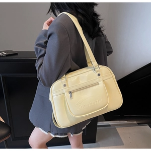 Detail of light yellow PU leather shoulder bag with embossed logo and smooth glossy finish