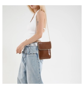 Detail view of brown leather vertical phone bag with gold chain trim and chain strap