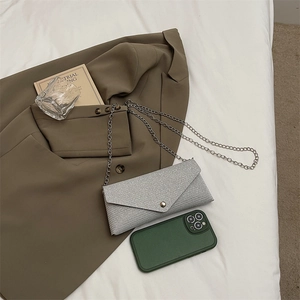 Sparkly silver glitter envelope phone bag with chain strap on minimalist background
