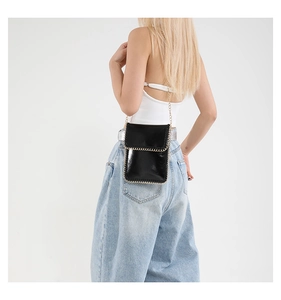 Close-up of a mini punk crossbody bag with shiny finish and gold chain strap detail