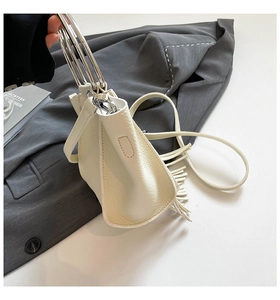 Detail of cream lychee leather handbag with silver rings, fringe, and thin shoulder strap