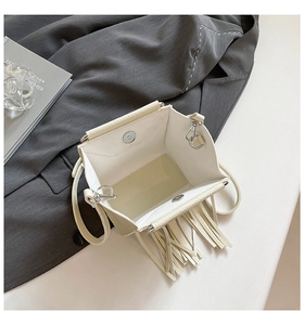 Dettaglio borsa in pelle color bianco crema con chiusura magnetica e lunghe frange