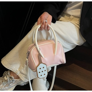 Detailed view of a pink Boston bag with white handles and a racket-shaped charm