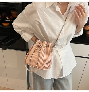 Detail of light pink pleated drawstring bucket bag with silver metal chain shoulder strap