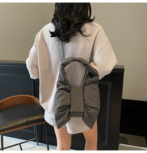 Detail view of a large dark grey puffy bow shoulder bag with lightweight fabric texture