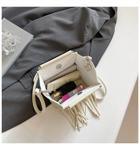 Detailed interior view of white pebbled leather shell bag with tassel showing storage capacity