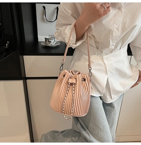 Detail of pink pleated bucket bag featuring drawstring closure and silver chain strap