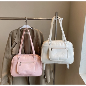 Détail de sacs à bandoulière en similicuir rose et blanc cassé avec logo embossé