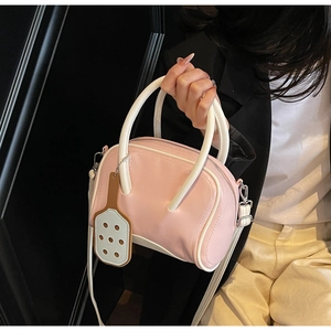 Detail of pink bowling bag featuring white handles and unique tennis racket charm accessory