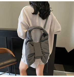 Detail of the oversized bow-shaped tote bag in dark grey with a puffy nylon texture
