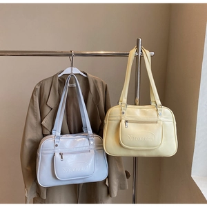 Détail de sacs bandoulière en cuir brillant avec poche zippée avant et logo