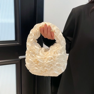 Elegant cream ruffled lace handbag with satin sheen and tiered pleats held by a model