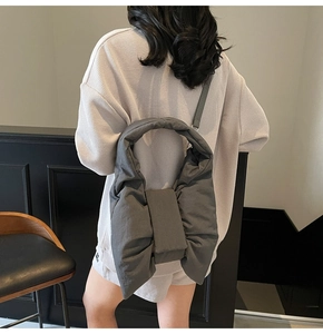 Detailed view of dark gray nylon bow-shaped puffy tote bag on model shoulder