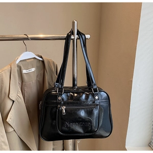 Detail of glossy black leather messenger bag featuring zipper pocket and Noronoro logo