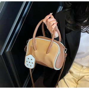 Close-up of contrast color mini Boston bag featuring creative paddle pendant and top handles