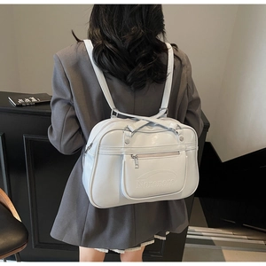 Détail du sac à dos messager en cuir verni blanc porté par un mannequin