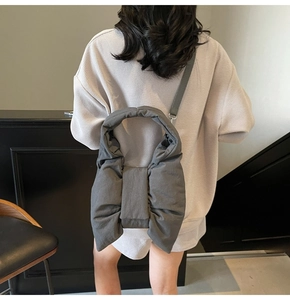 Detail of grey puffy nylon shoulder bag with bow design and adjustable strap