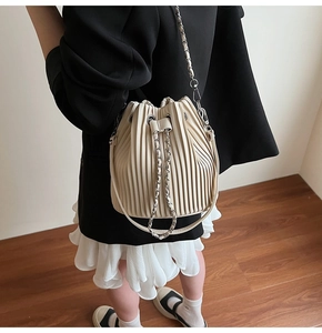Detailed view of the pleated beige bucket bag with silver chain and drawstring closure